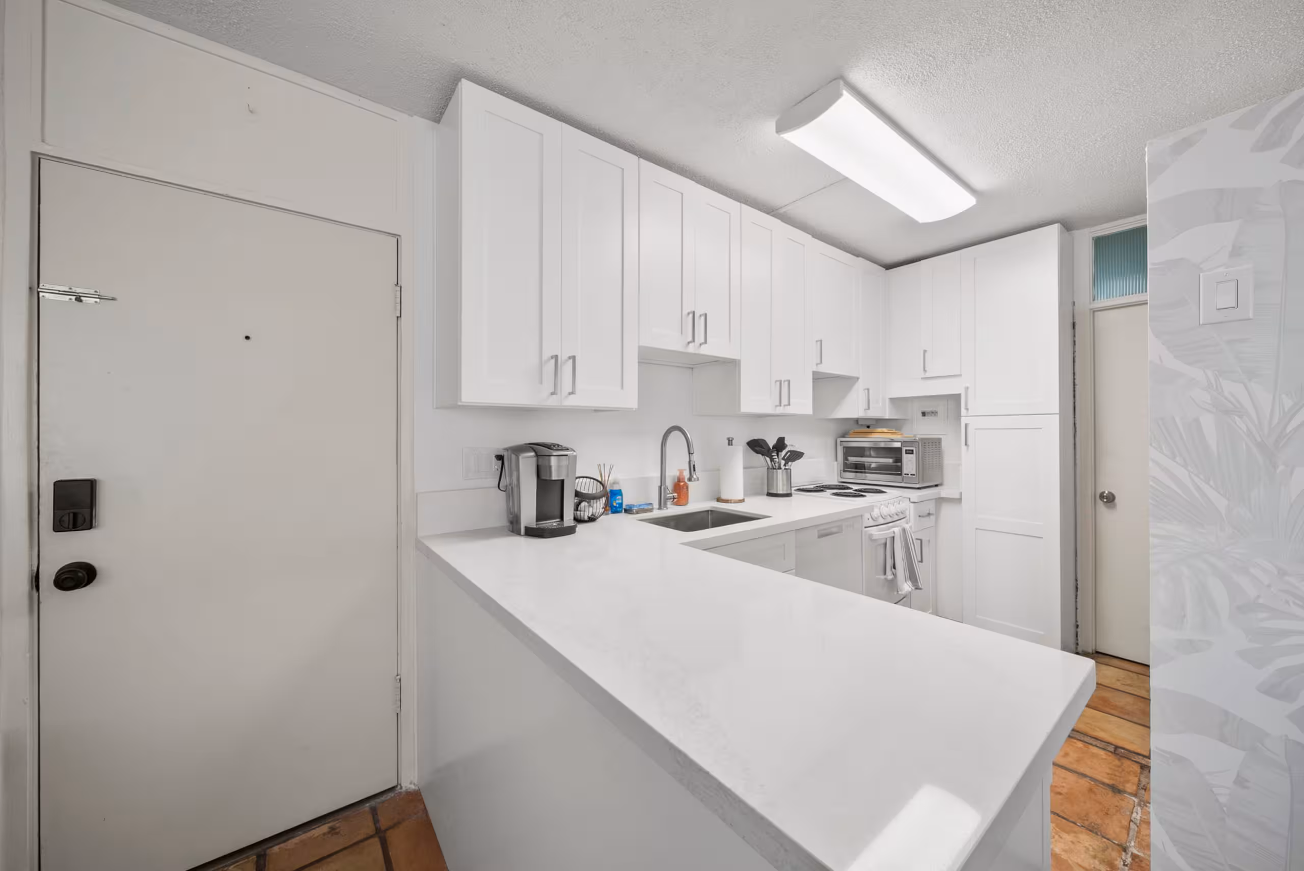 Updated white kitchen with a broad quartz peninsula
