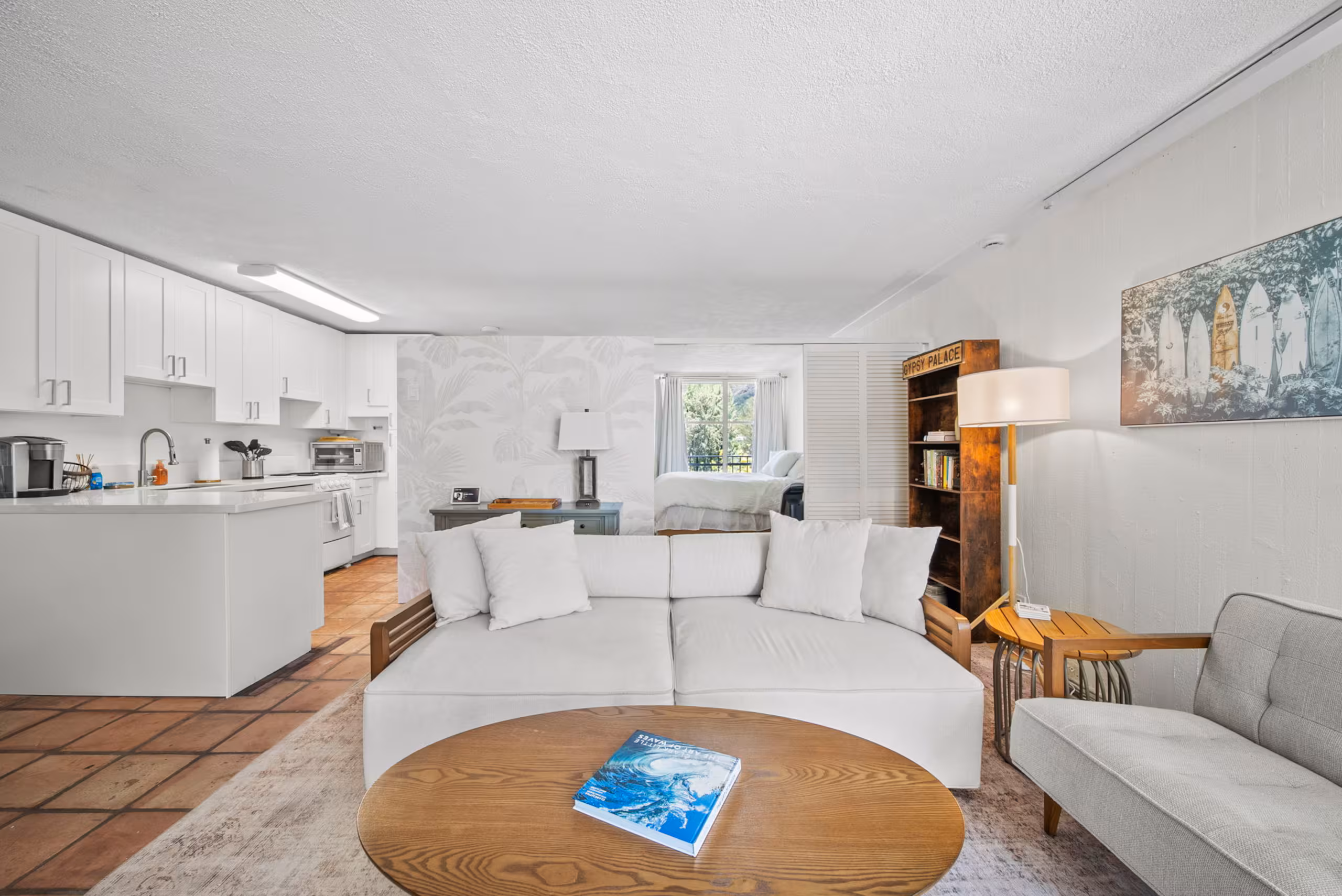 White living room with the updated kitchen and bedroom beyond