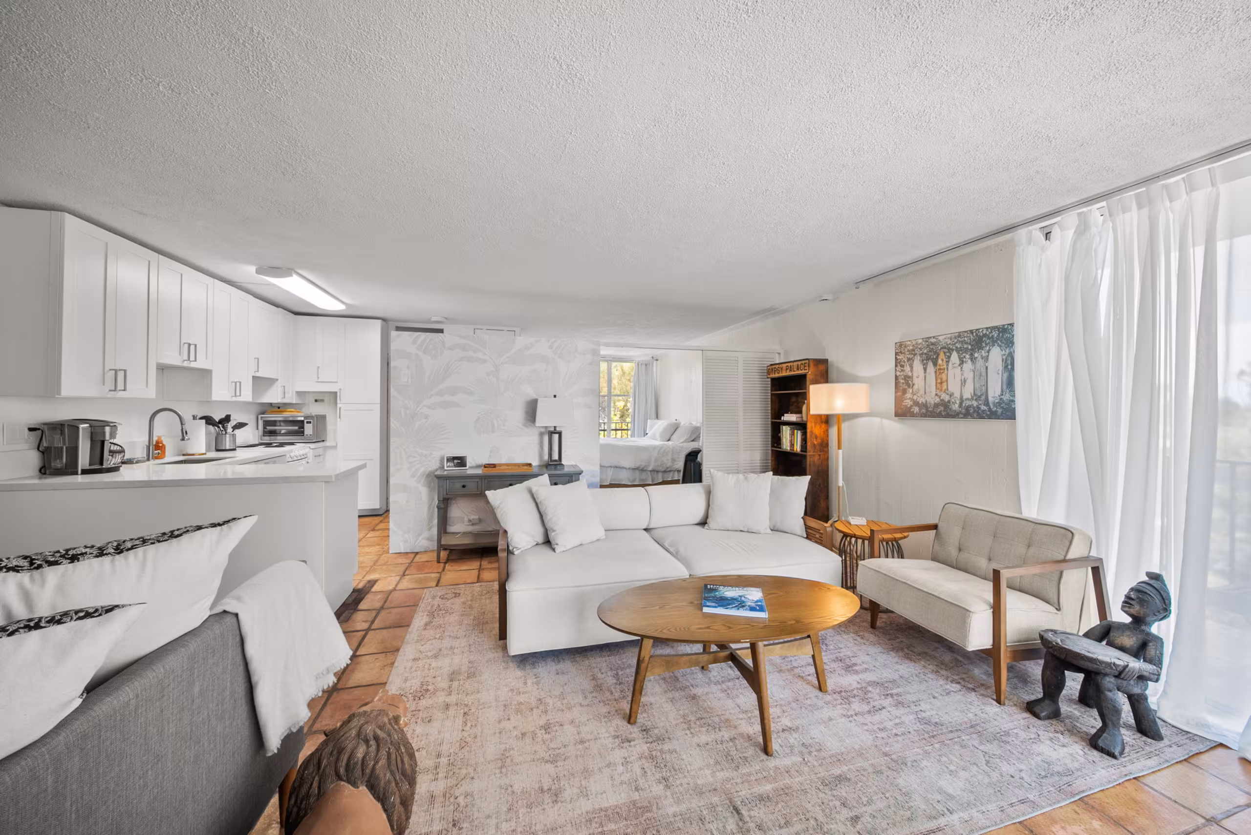 Bright white living room with the updated kitchen and lānai beyond